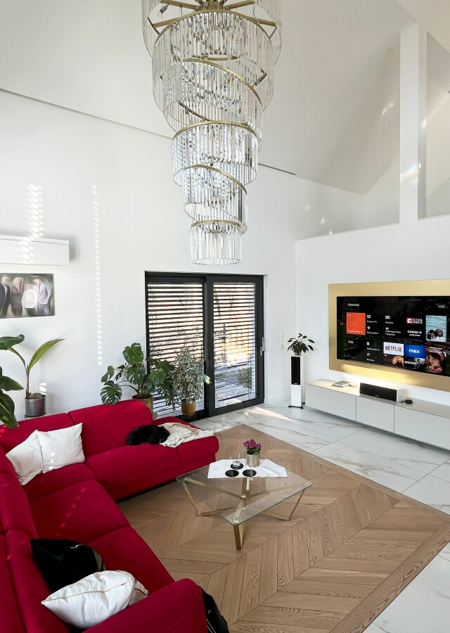 prywatne kino w pokoju dziennym. Realizacja kino w salonie Kraków - przestronne, nowoczesne wnętrze z nagłośnieniem i czerwonym narożnikiem.